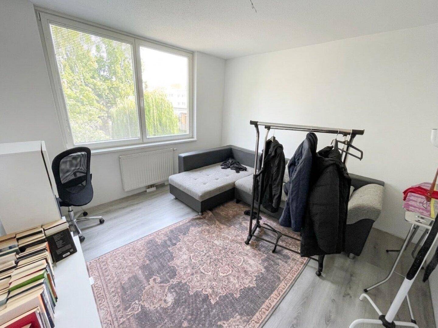 Helles Zimmer, nutzbar als Büro oder Gästezimmer, mit Sofa und großem Fenster.