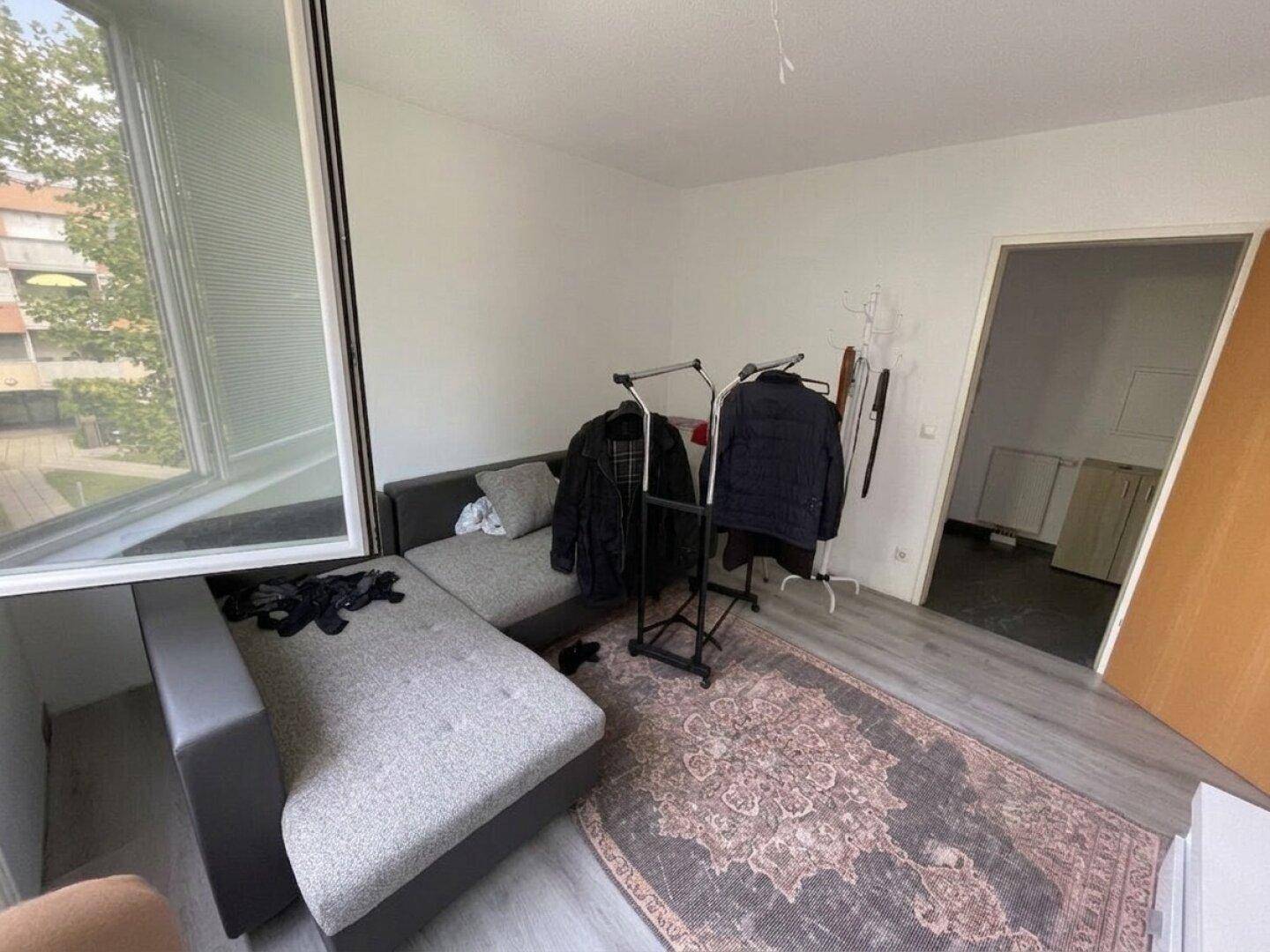 Flexibel nutzbares Zimmer mit Sofa und geöffnetem Fenster für frische Luft.