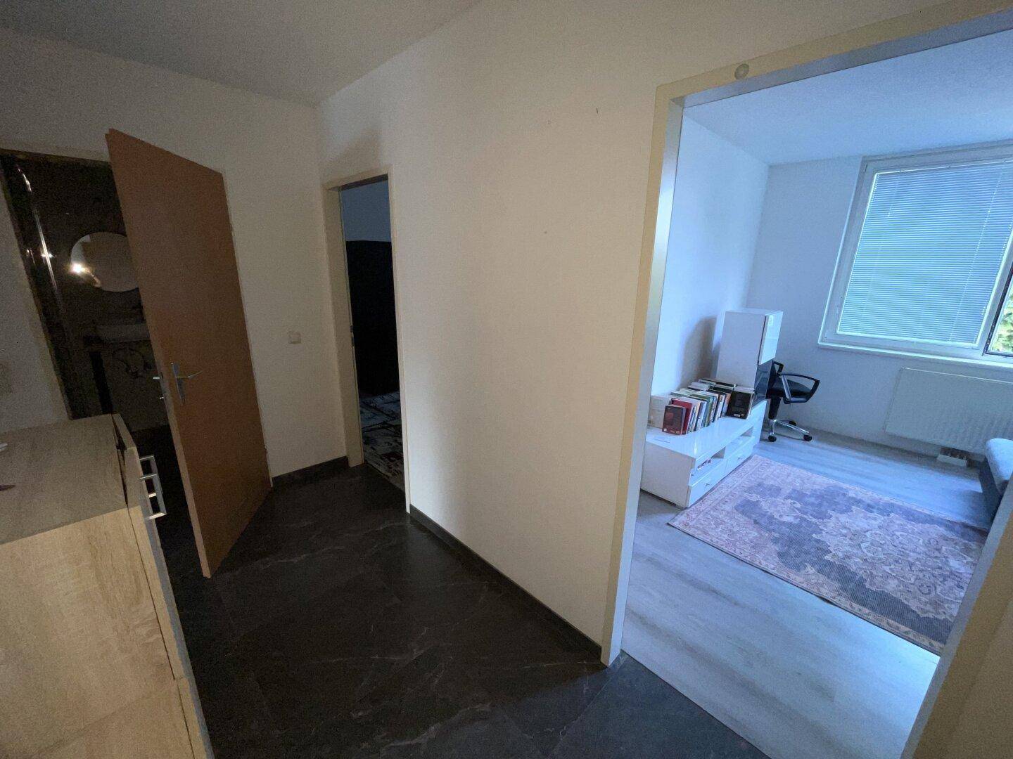 Flur mit dunklem Fliesenboden, der zu den angrenzenden Zimmern führt.
