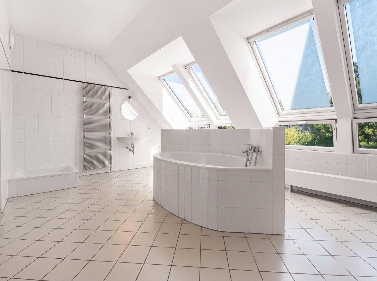 Geräumiges Badezimmer mit Badewanne, weißen Fliesen und Dachfenstern für viel Tageslicht.