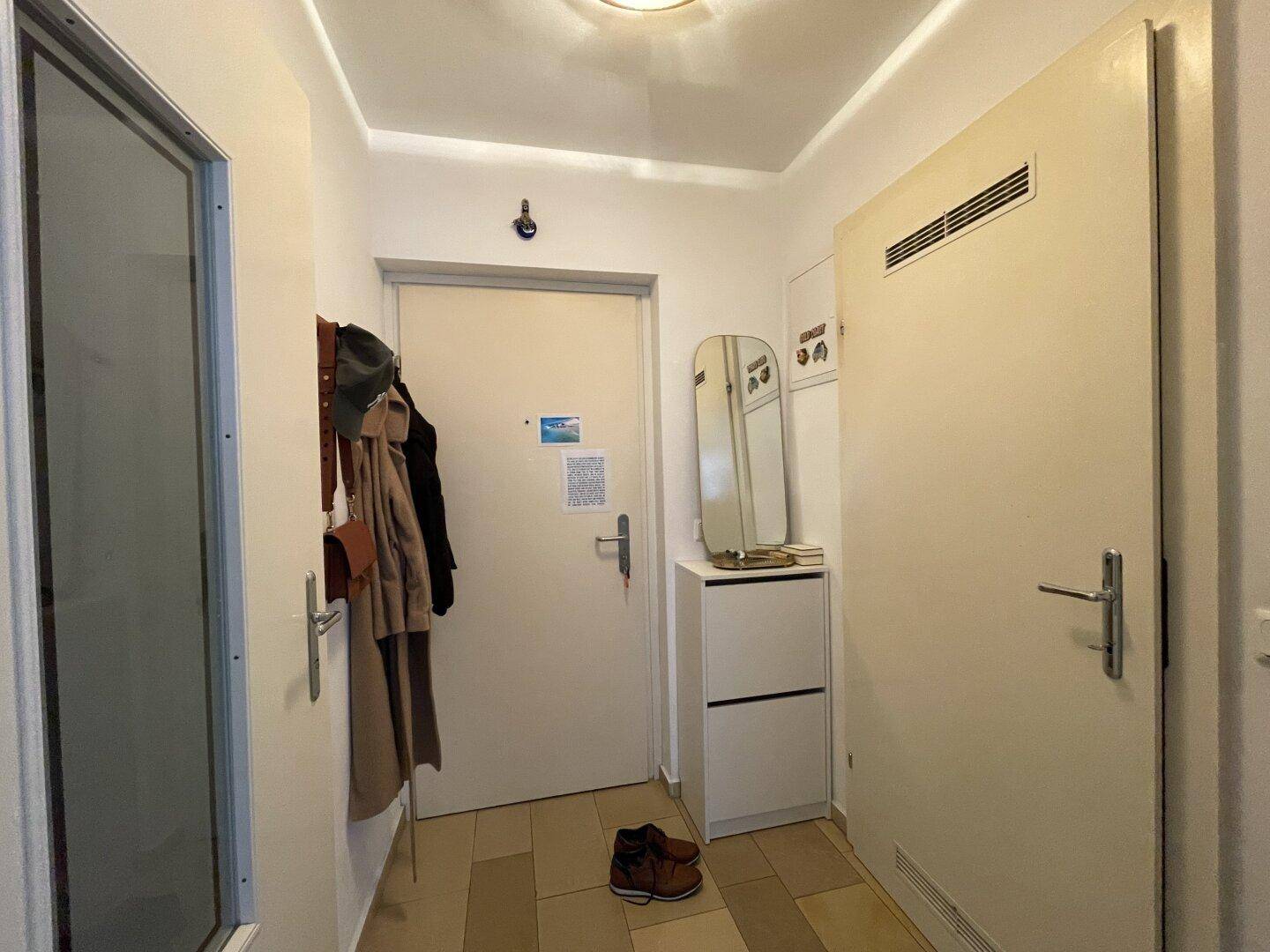 Heller Eingangsbereich mit Garderobe, Schuhschrank und Fliesenboden, bietet Stauraum.