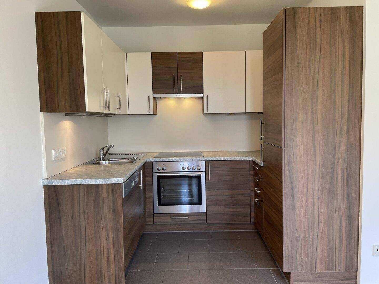 Moderne Einbauküche mit Holz- und weißen Fronten, ausgestattet mit Backofen und Spülmaschine.