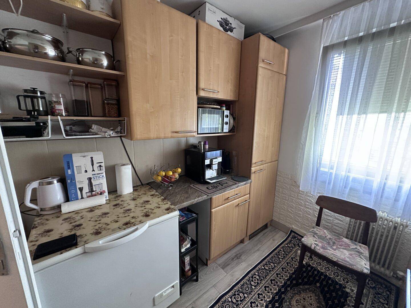 Praktische Küche mit Holzschränken, Kühlschrank und ausreichend Arbeitsfläche.