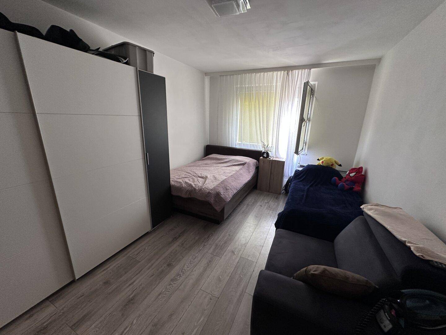 Helles Schlafzimmer mit zwei Betten und einem großen Kleiderschrank, gut beleuchtet durch das Fenster.