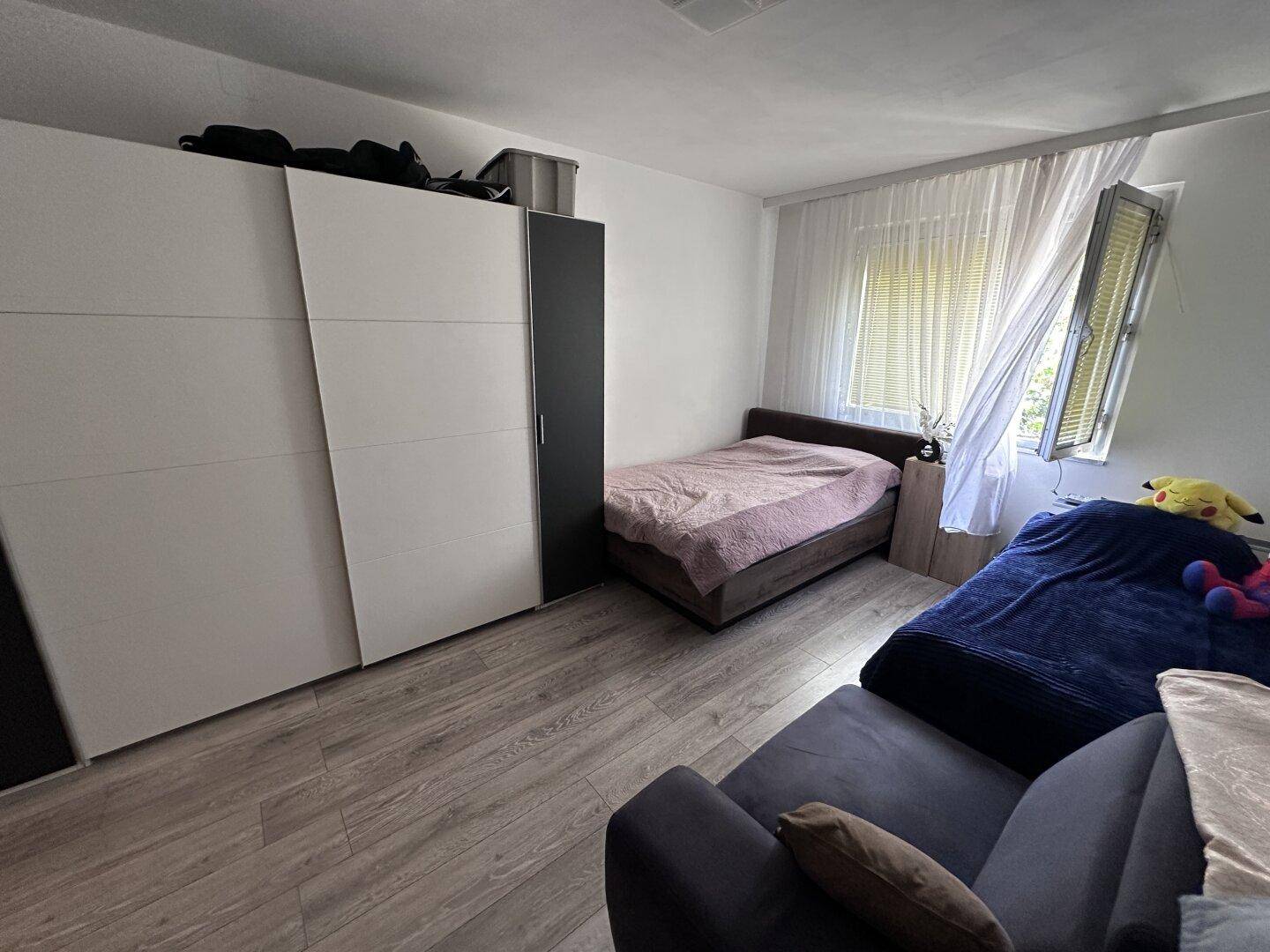 Schlafzimmer mit zwei Betten, großem Schiebetürenschrank und hellem Laminatboden.