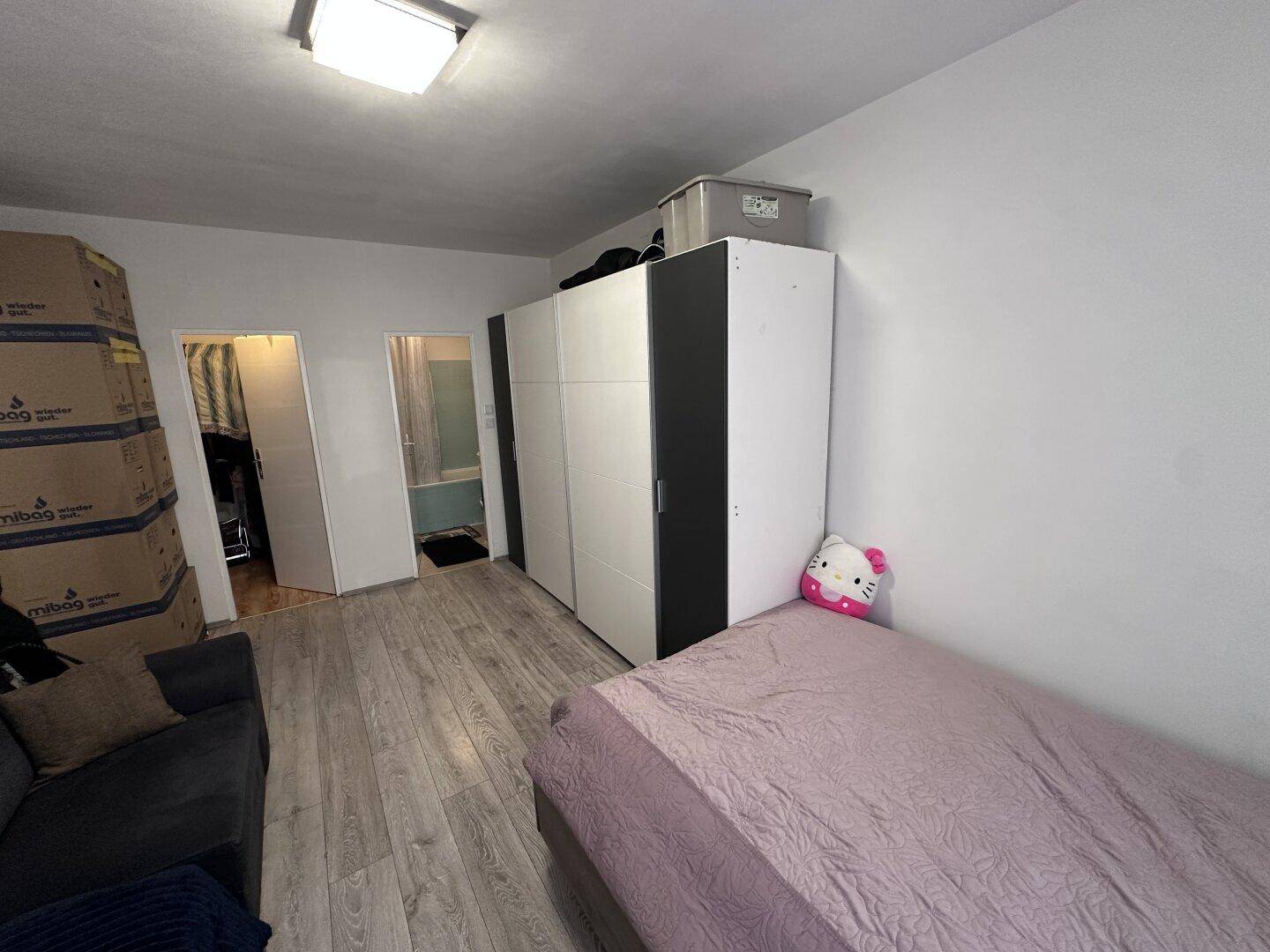 Schlafzimmer mit großem Kleiderschrank und Zugang zu weiteren Räumen, inklusive Bad.