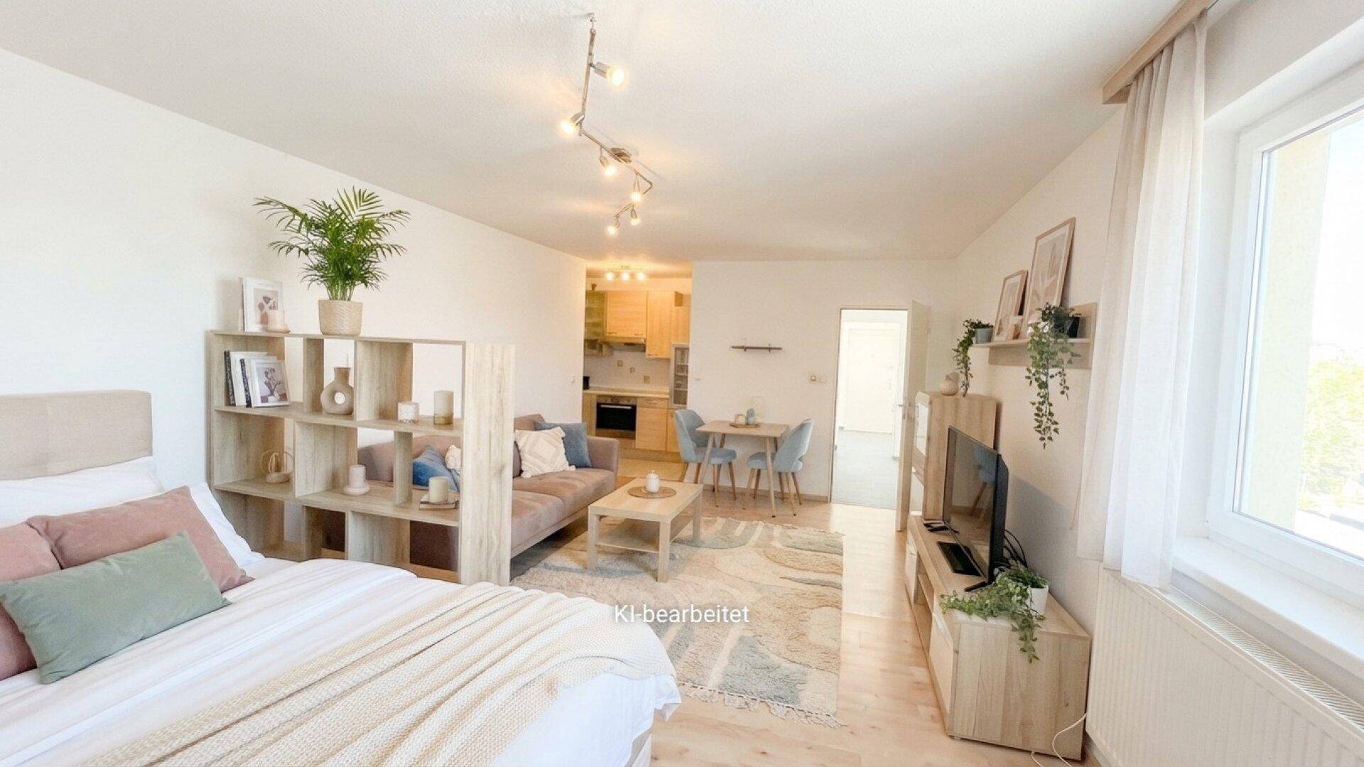 Helles Studio-Apartment mit offenem Wohn-, Ess- und Schlafbereich sowie kleiner Küche im Hintergrund.
