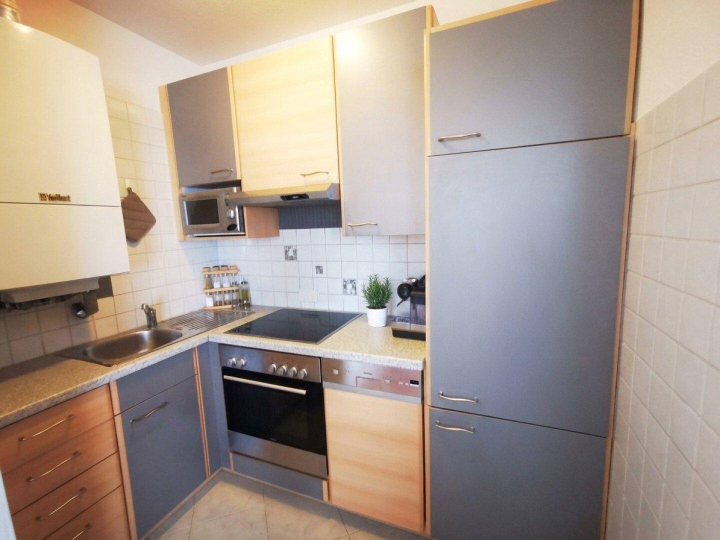 Funktionale Einbauküche mit modernen grauen und holzfarbenen Schränken und Geräten.