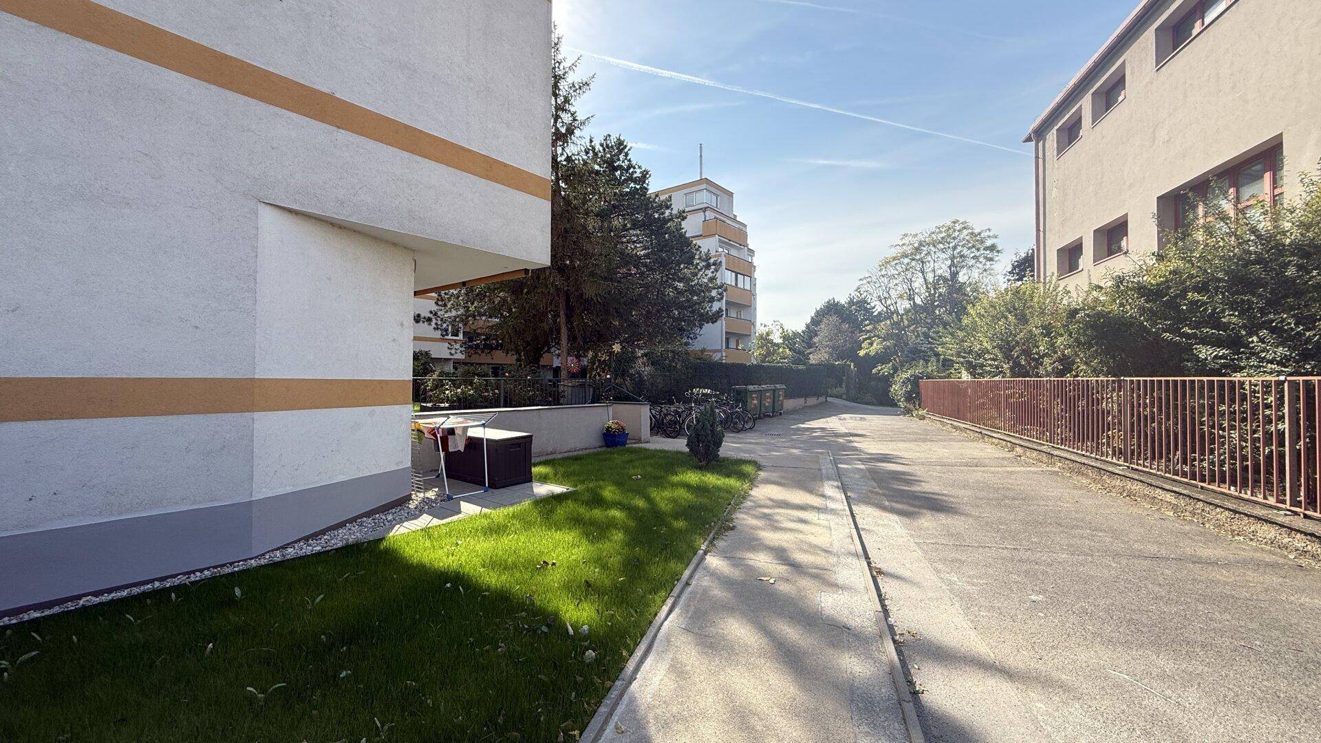 Seitenansicht eines Wohngebäudes mit Gehweg und umliegender Vegetation.