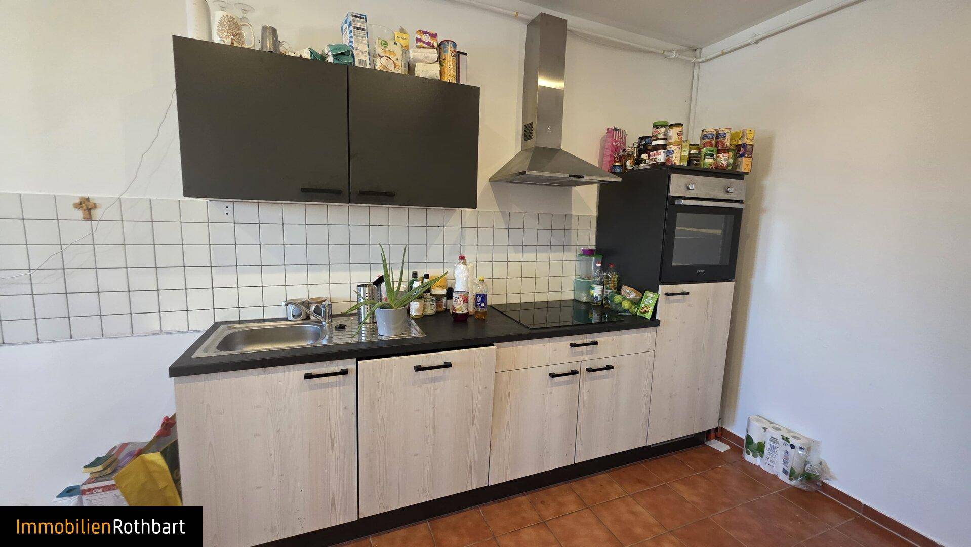 Moderne Küche mit hellen Holzfronten, dunkler Arbeitsplatte und Edelstahl-Dunstabzugshaube.