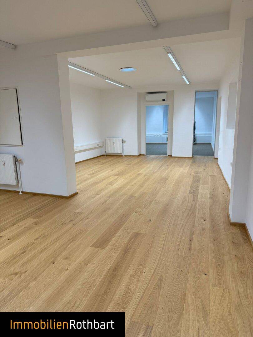 Großer, heller Büroraum mit Holzboden und moderner Beleuchtung, bereit zur Einrichtung.