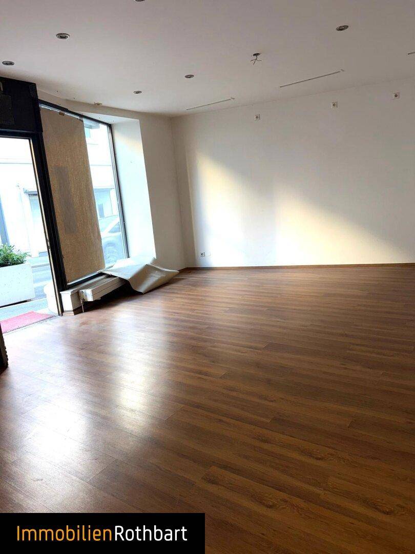 Geräumiger Geschäftsraum mit Laminatboden und weißen Wänden, ideal für verschiedene Nutzungskonzepte.