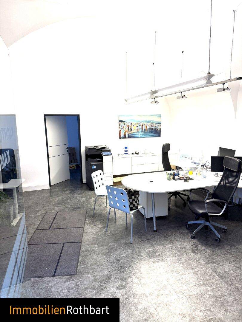 Helles Büro mit gewölbter Decke, modernen Möbeln und einem Drucker im Hintergrund des Raumes.