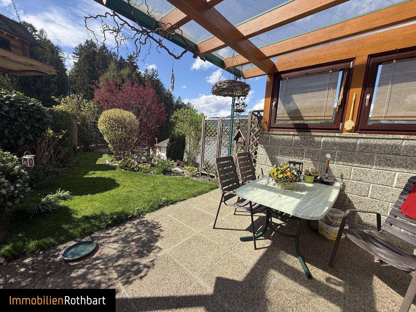 Überdachte Terrasse mit Sitzgelegenheiten und Blick in den gepflegten Garten.