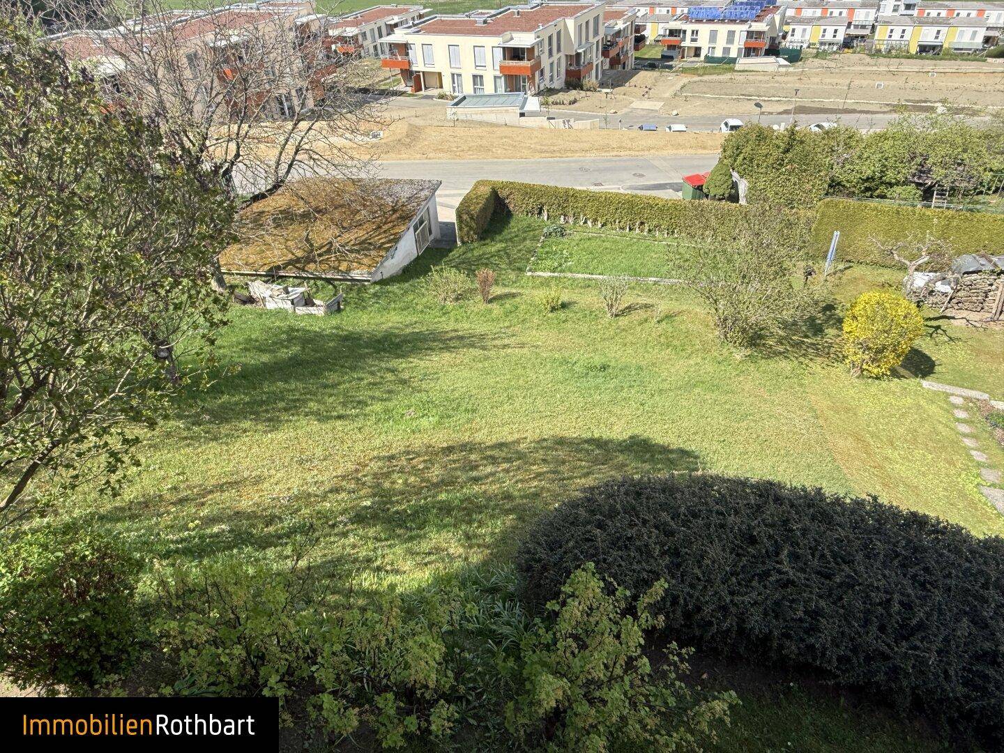 Weitläufiger Gartenbereich mit Rasenflächen und Blick auf die Nachbarschaft.