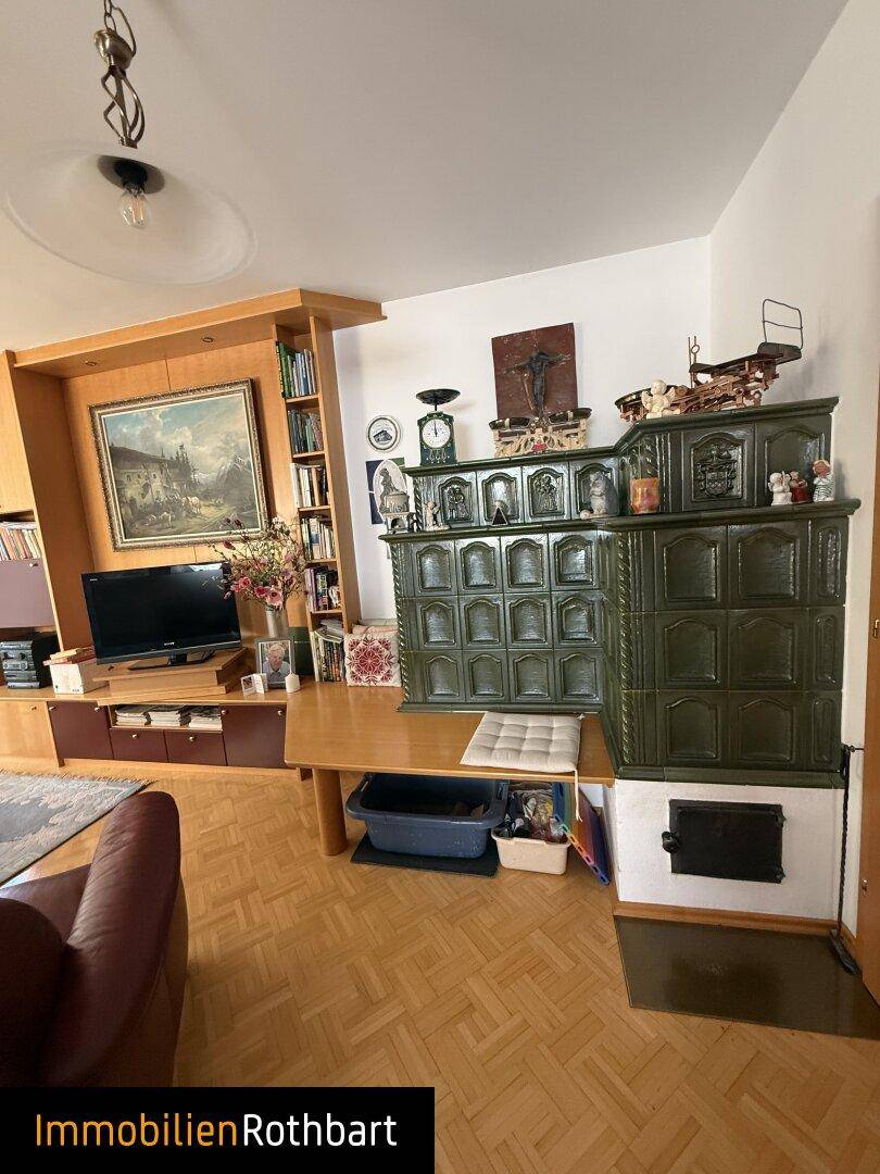 Gemütliches Wohnzimmer mit traditionellem Kachelofen und Holzparkettboden.