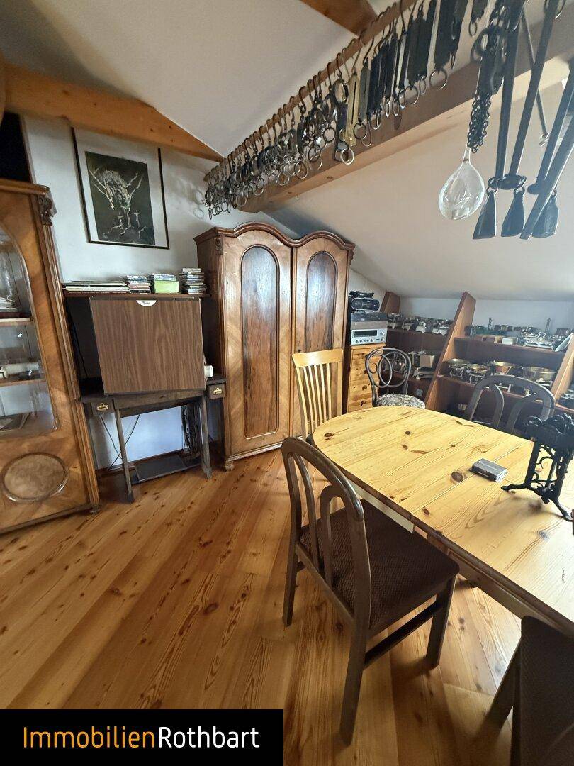 Geräumiger Dachbodenbereich mit Holzboden, antiken Möbeln und Dachschrägen.