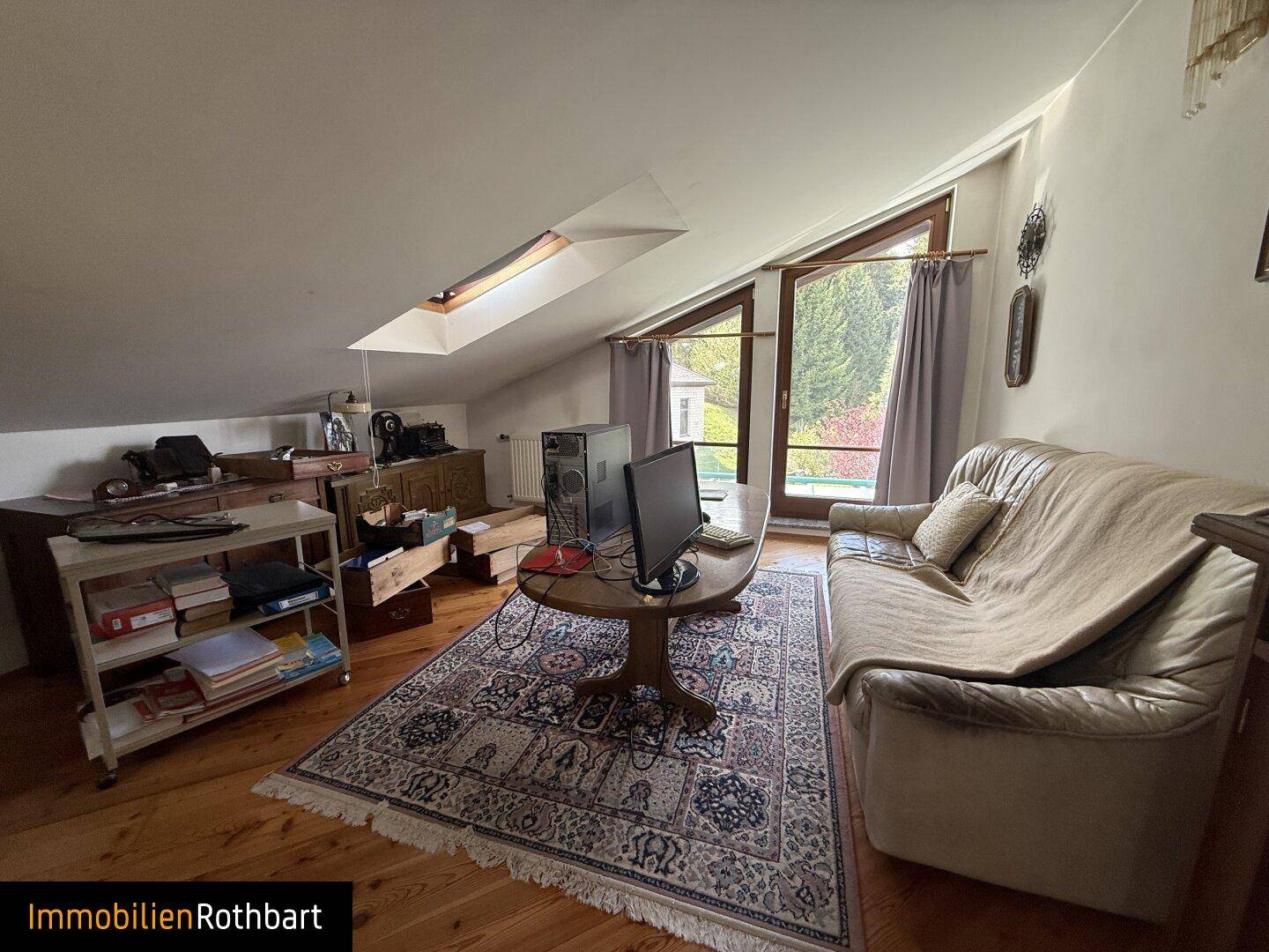 Heller Dachboden mit Schreibtisch, Sofa und Dachfenstern für natürliches Licht.