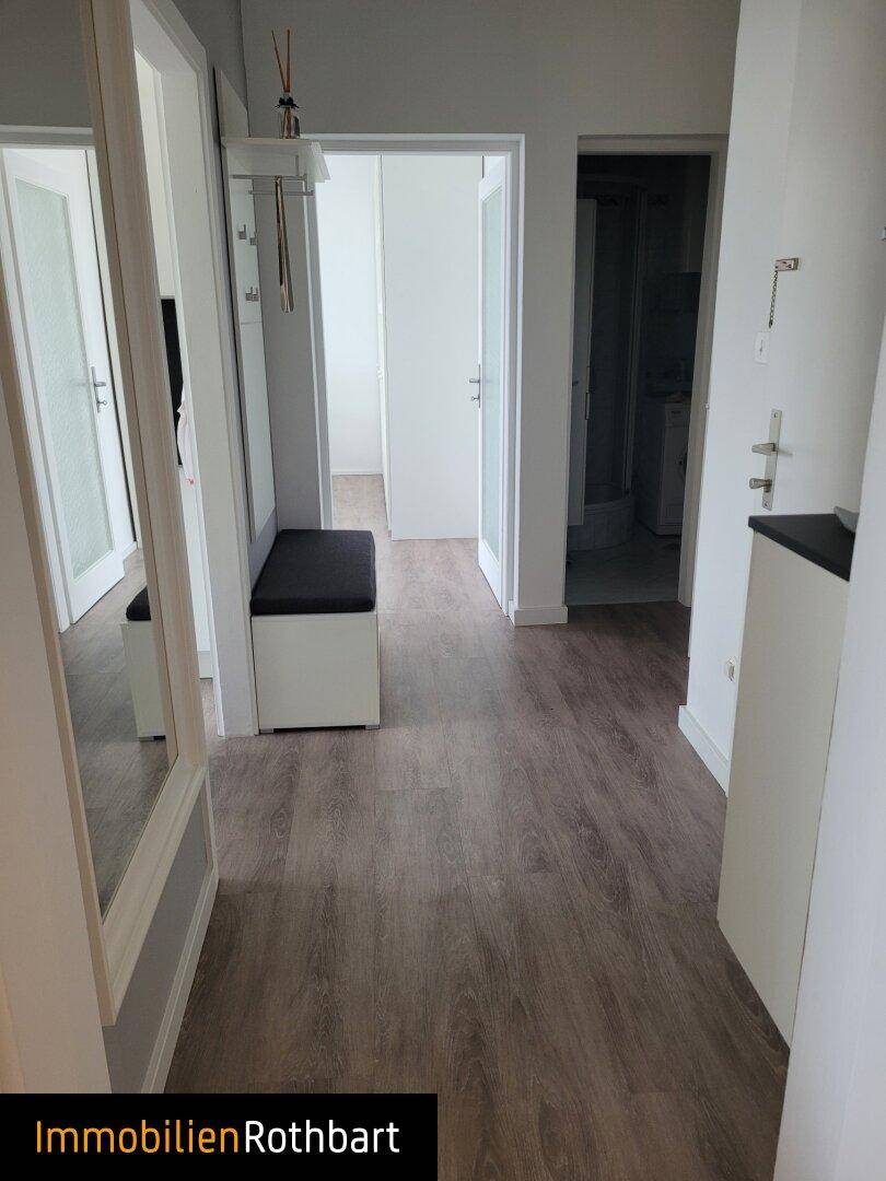 Geräumiger Flur mit Spiegel, Garderobe und Laminatboden, der zu verschiedenen Zimmern führt.