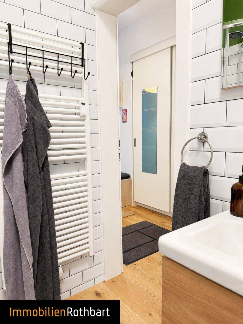 Modernes Badezimmer mit weißen U-Bahn-Fliesen, Waschbecken und beheiztem Handtuchhalter.