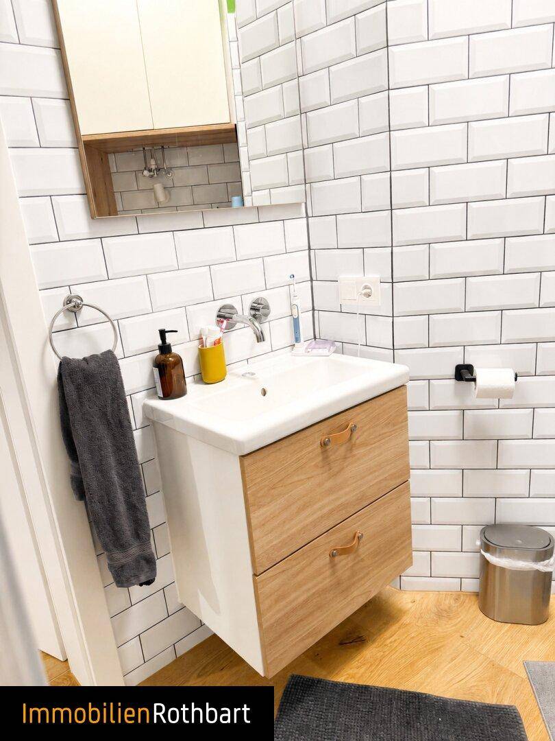 Modernes Badezimmer mit weißen U-Bahn-Fliesen, Holzwaschtisch und Spiegelschrank.