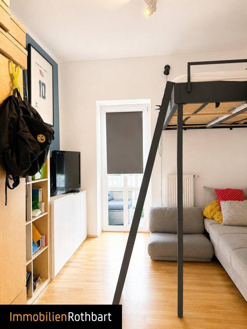 Schlafzimmer mit Hochbett, Sofa und Holzfußboden, mit Zugang zu einem Balkon.