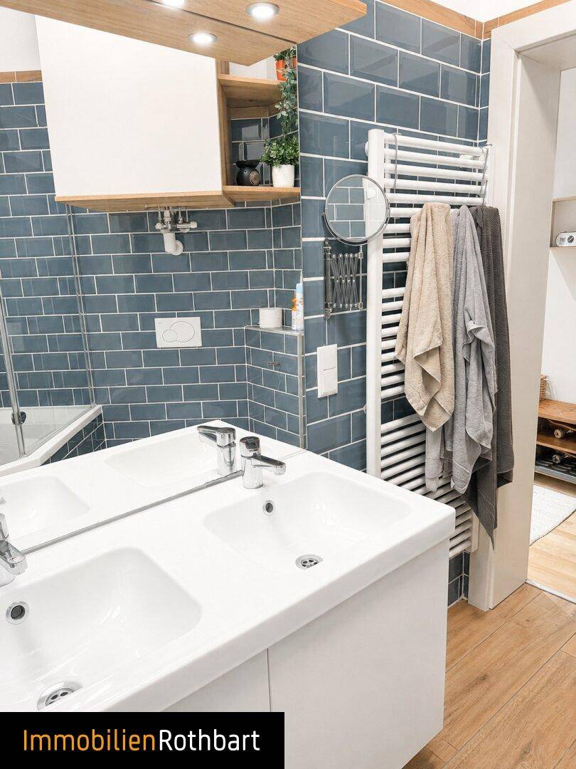 Badezimmer mit Doppelwaschbecken, blauen U-Bahn-Fliesen und beheiztem Handtuchhalter.