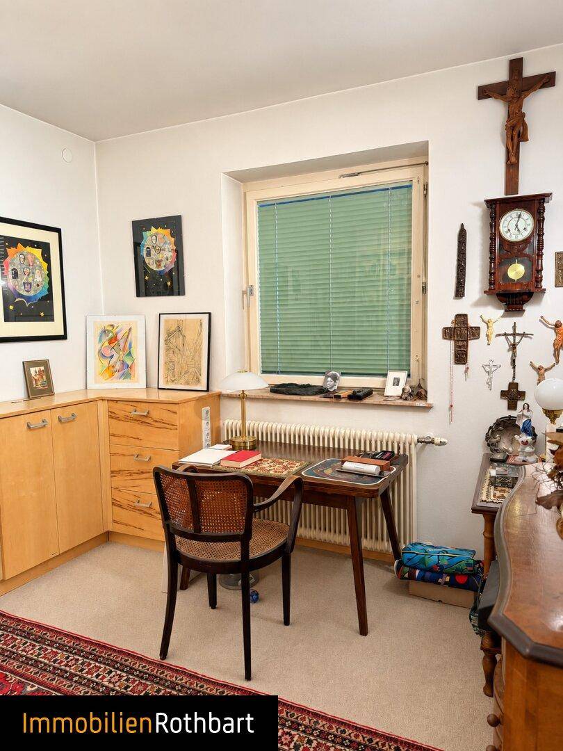 Ruhiges Arbeitszimmer mit Schreibtisch, Stauraum und traditioneller Dekoration am Fenster.