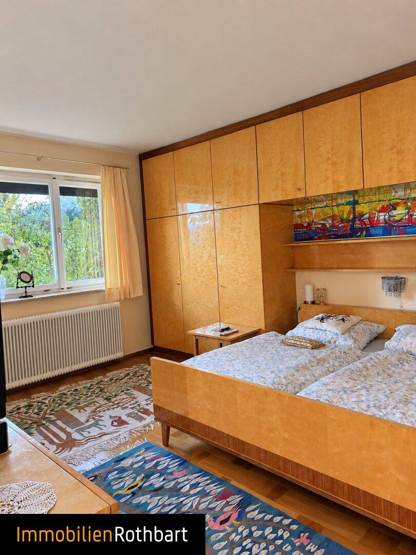 Schlafzimmer mit zwei Einzelbetten, Einbauschränken und Blick ins Grüne durch das Fenster.