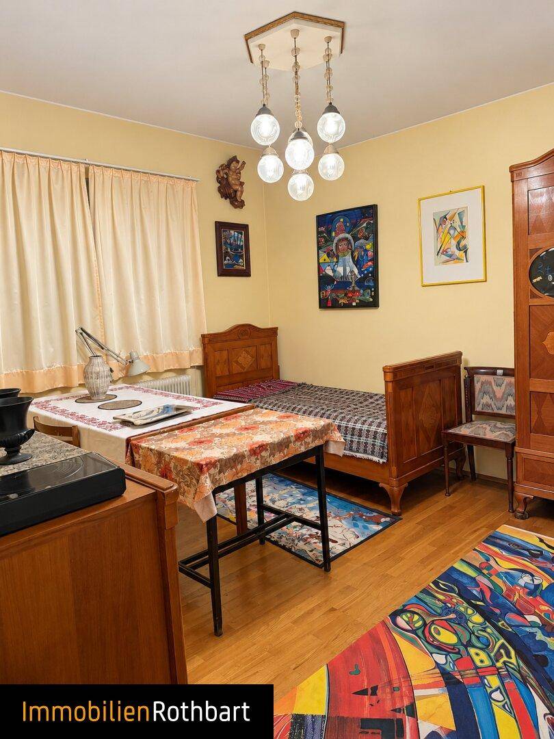 Helles Schlafzimmer mit zwei Einzelbetten, Holzboden und traditionellen Möbeln.