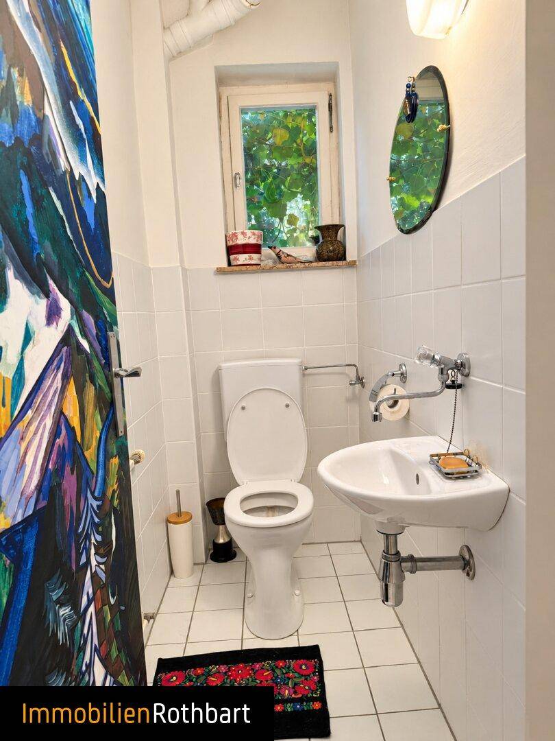 Kleines Gäste-WC mit Fenster, weiß gefliest und mit minimalistischem Waschbecken.