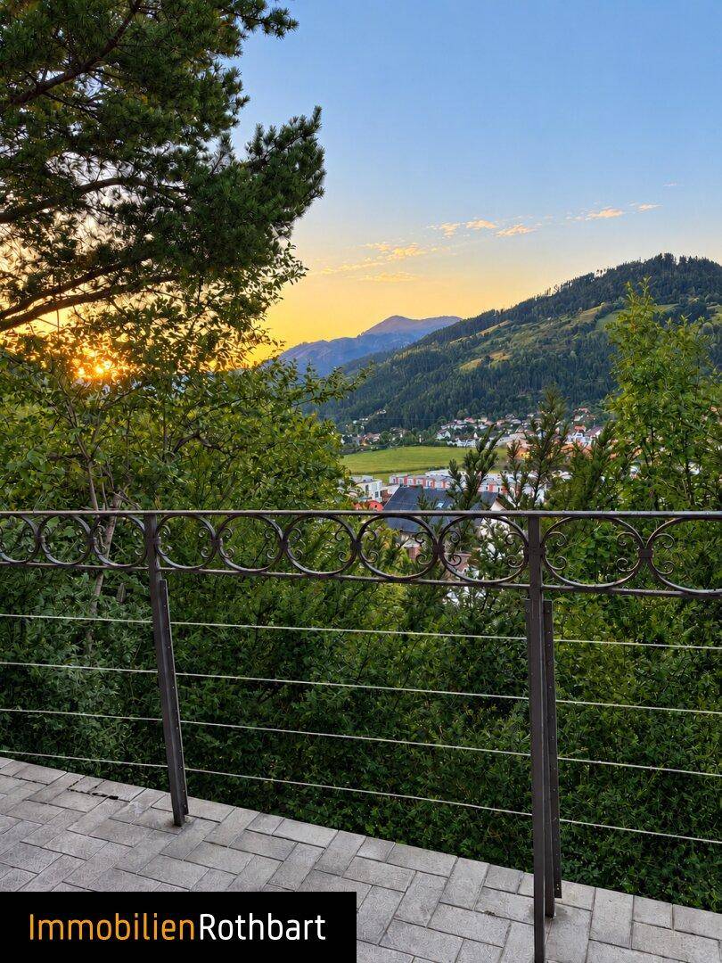 Terrasse mit Bergblick und üppiger grüner Umgebung bei Sonnenuntergang.
