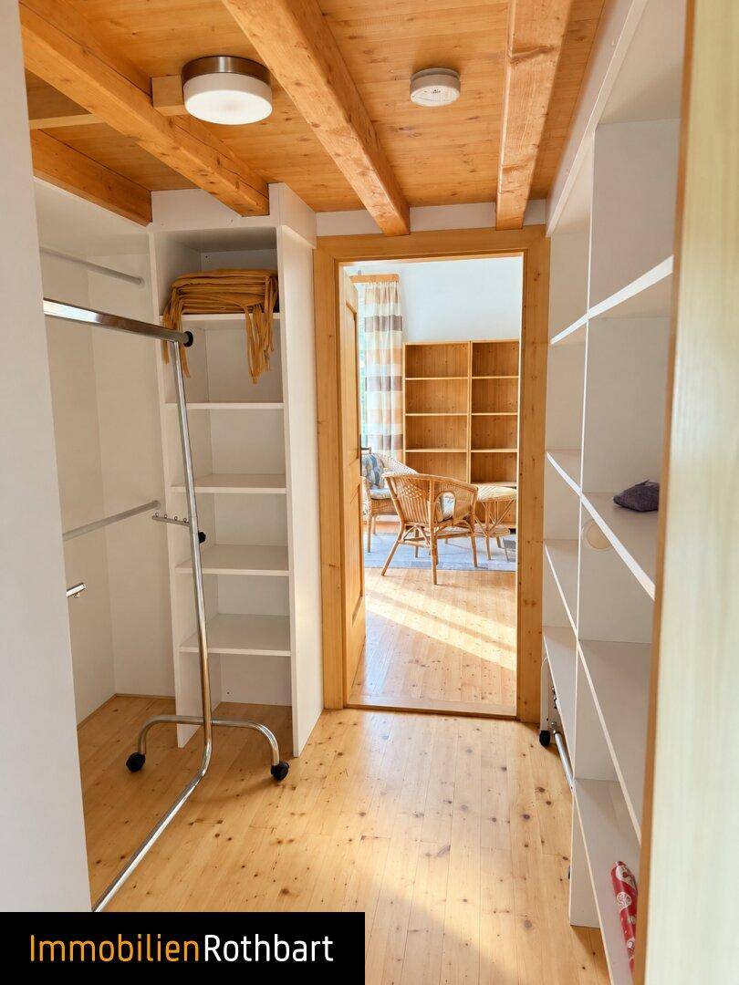 Geräumiger begehbarer Kleiderschrank mit offenen Regalen und Holzfußboden.