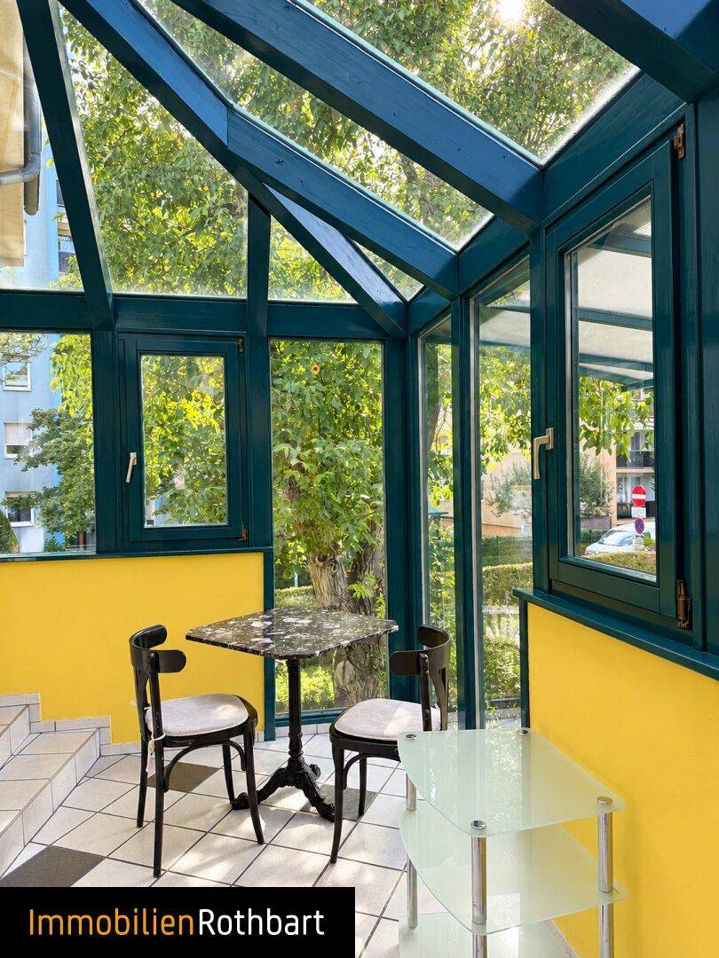 Heller Wintergarten mit gelben Wänden, Glasdach und kleinem Tisch für gemütliche Stunden.