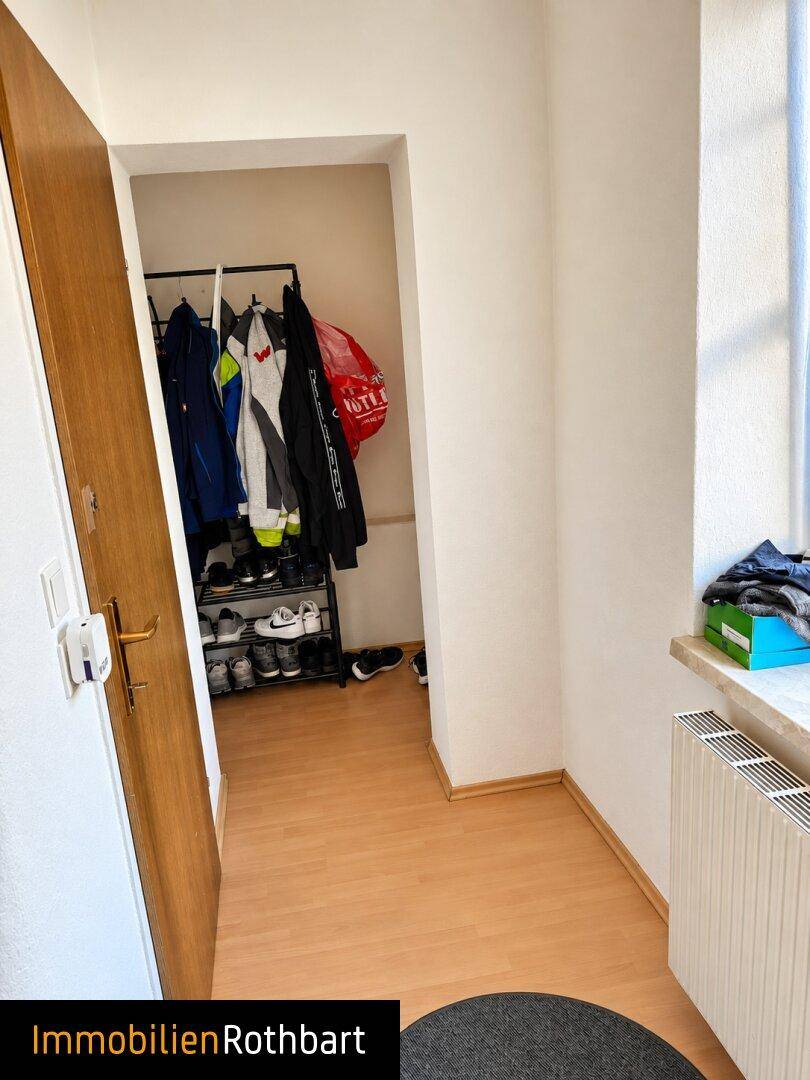 Heller Flur mit Laminatboden, Garderobe und einem Heizkörper unter dem Fenster.