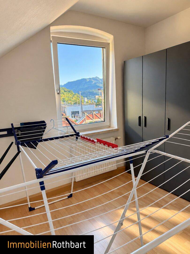 Hauswirtschaftsraum im Dachgeschoss mit Wäscheständer und Schränken, hell durch das Fenster.