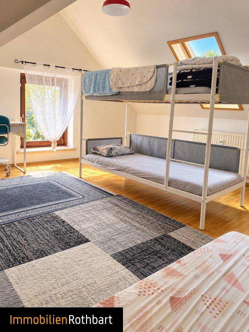 Kinderzimmer im Dachgeschoss mit Etagenbett, Holzboden und Dachfenster für viel Licht.