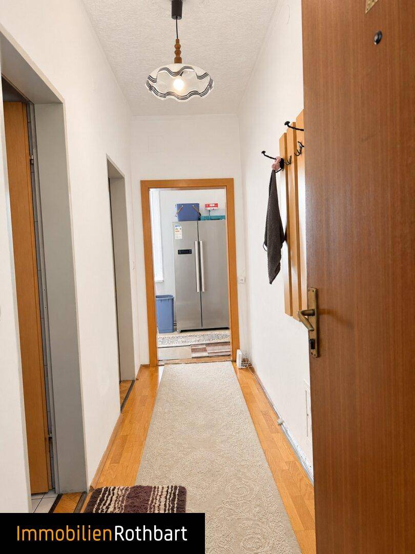Heller Flur mit Holzfußboden und Garderobe, der zu weiteren Räumen führt.