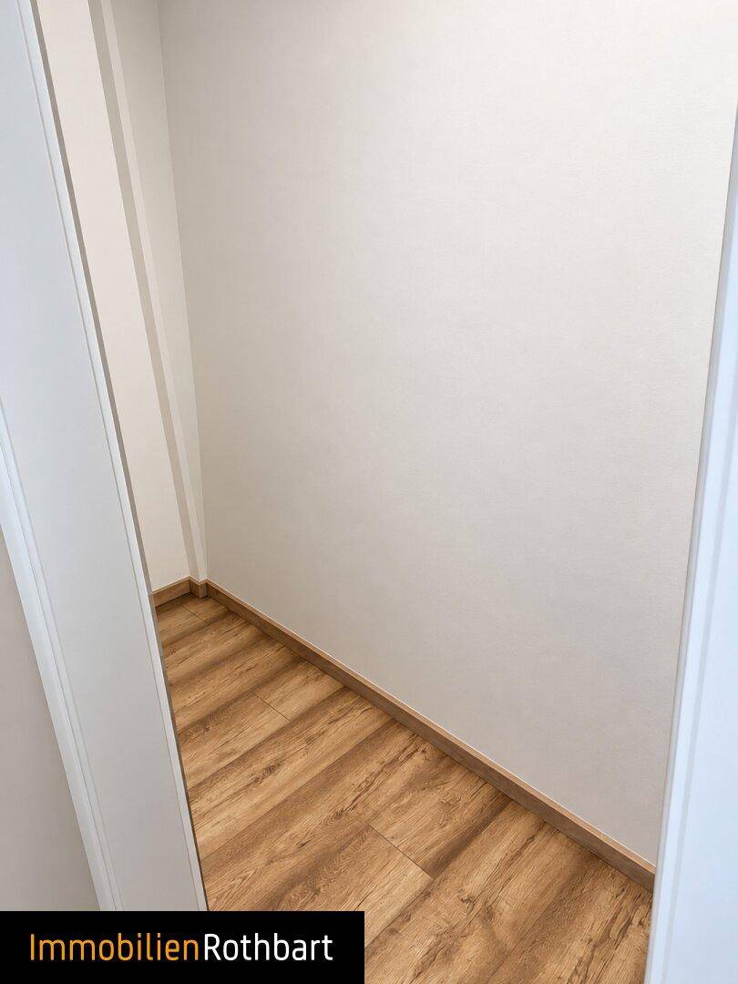 Kleiner, leerer Abstellraum mit Laminatboden und weißen Wänden.