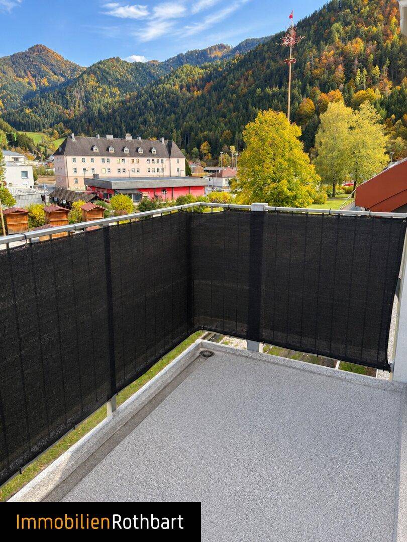 Balkon mit schwarzem Sichtschutz und einem malerischen Blick auf die umliegende Berglandschaft.