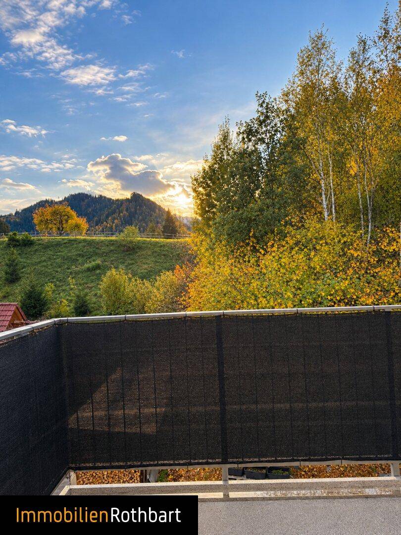 Sonniger Balkon mit weitem Blick auf die herbstliche Berglandschaft und den Himmel.