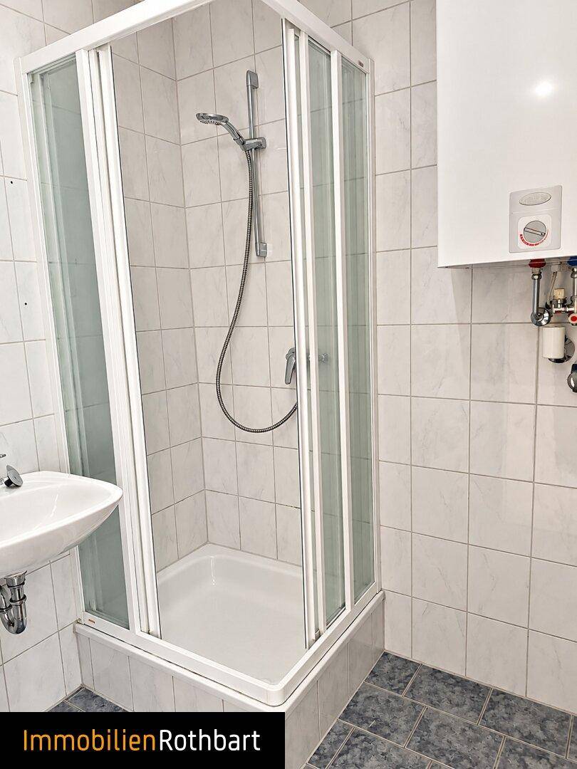 Modernes Badezimmer mit Duschkabine, Waschbecken und weiß gefliesten Wänden.