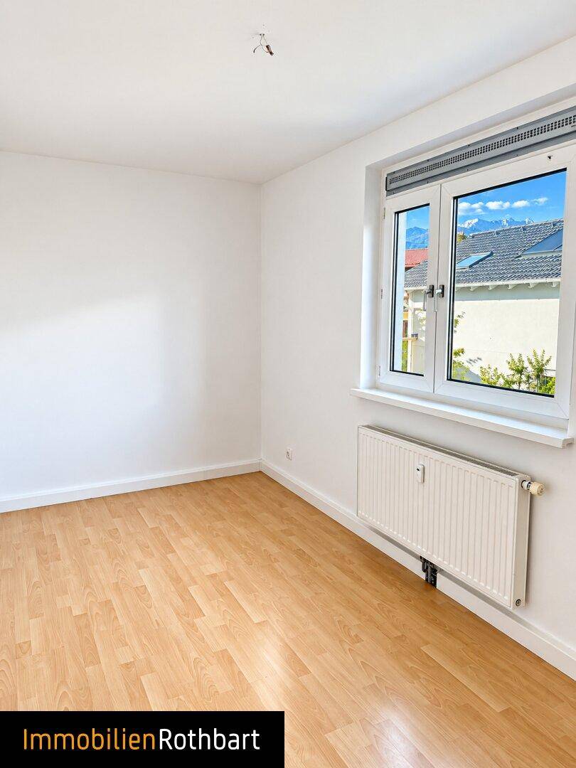 Geräumiges Zimmer mit Laminatboden und Fenster, das viel Tageslicht hereinlässt.