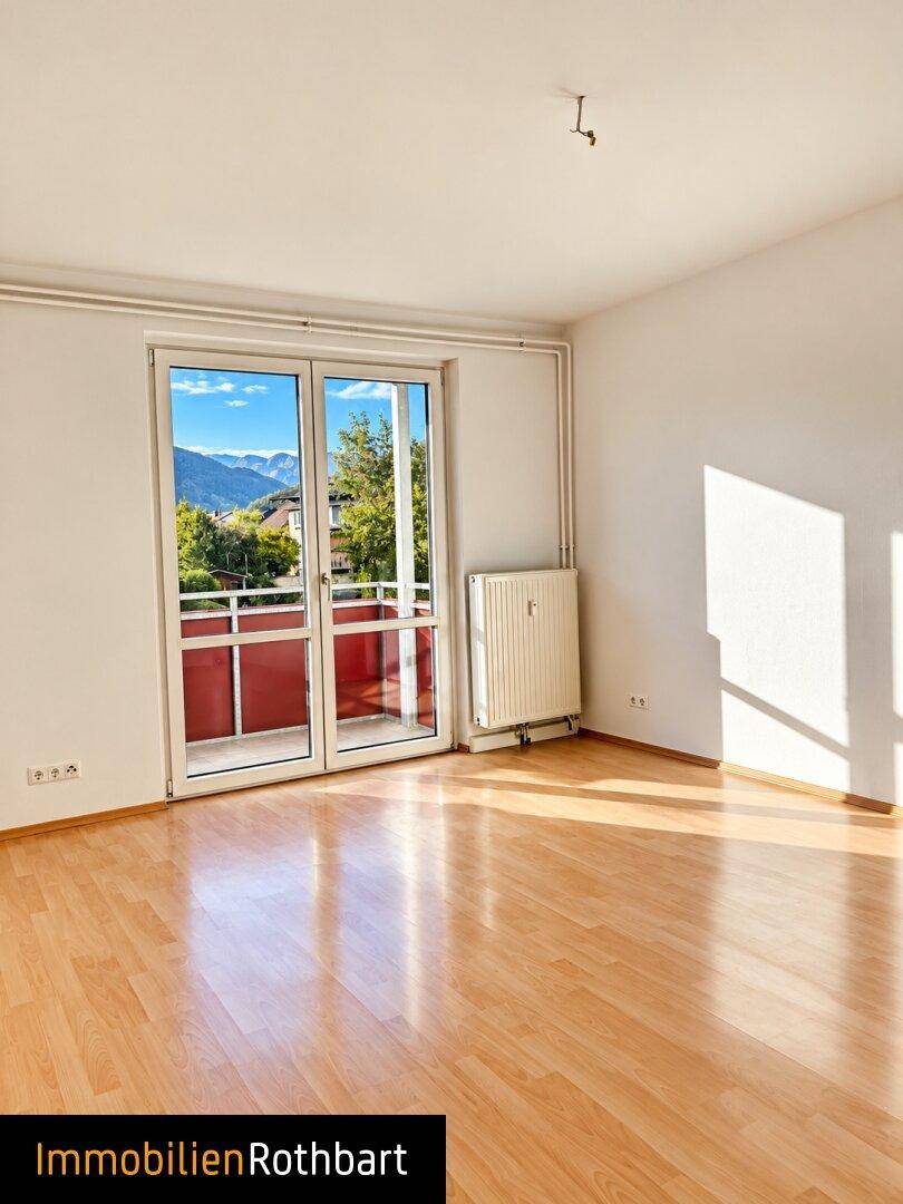 Lichtdurchflutetes Zimmer mit Laminatboden und Blick auf die umliegende Berglandschaft.