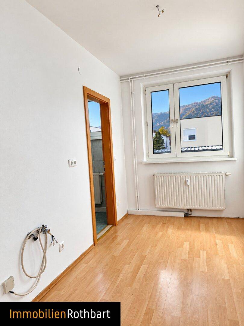 Kleiner Raum mit Laminatboden und Anschlussmöglichkeiten, angrenzend an ein Badezimmer.