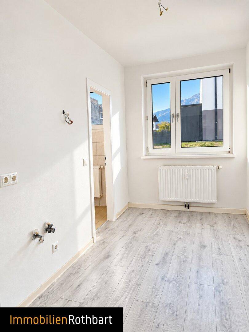 Heller Raum mit Laminatboden und Anschlüssen für eine Küche, mit Bergblick.