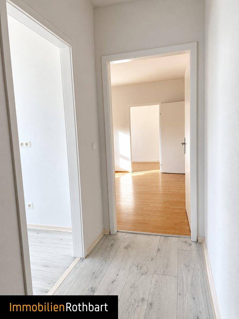 Heller Flur mit hellem Laminatboden, der zu weiteren Zimmern der Wohnung führt.