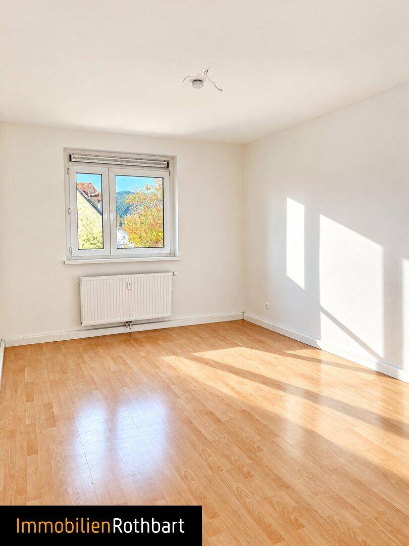 Freundliches Zimmer mit Laminatboden und Fenster, das viel Tageslicht hereinlässt.