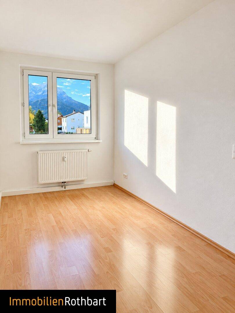 Lichtdurchflutetes Zimmer mit Laminatboden und Blick auf die umliegende Berglandschaft.