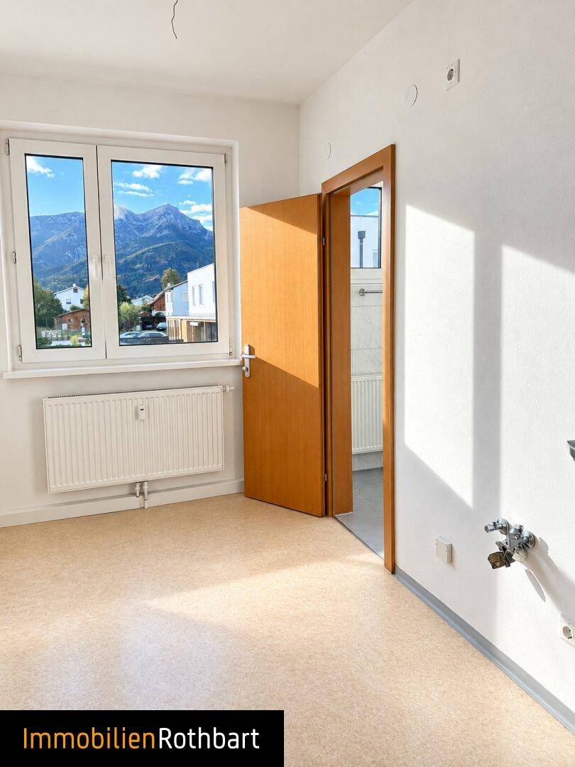 Zimmer mit Linoleumboden, Fenster mit Bergblick und vorbereiteten Anschlüssen.